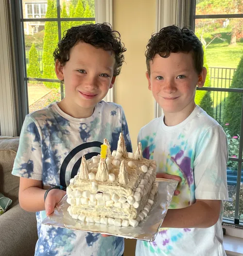 Two boys holding a cake decorated like a temple