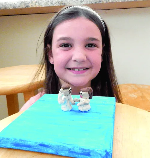 Smiling girl with her clay craft of a baptism scene