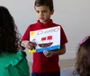 Boy showing others a picture he drew of a boat